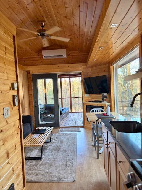 W160655 Hogback Rd Unit 5, Rusk Twp, WI 54728 - living room with wood ceiling, a wall mounted air conditioner, wooden walls, healthy amount of natural light, and ceiling fan