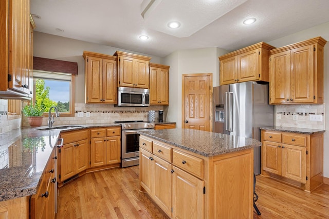 9015 Schutte Ct, Corcoran, MN 55340 - kitchen featuring stainless steel appliances, light wood-style flooring, a kitchen island, dark stone counters, and decorative backsplash