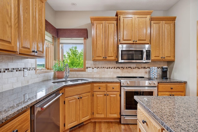 9015 Schutte Ct, Corcoran, MN 55340 - kitchen with appliances with stainless steel finishes, light stone counters, light wood finished floors, and tasteful backsplash