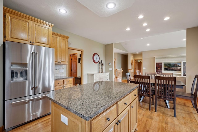 9015 Schutte Ct, Corcoran, MN 55340 - kitchen featuring high end fridge, light stone countertops, a kitchen island, light wood-style flooring, and recessed lighting