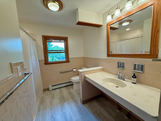 17535 Riverwood Dr, Little Falls, MN 56345 - bathroom featuring a baseboard radiator, tile walls, wood finished floors, vanity, and wainscoting