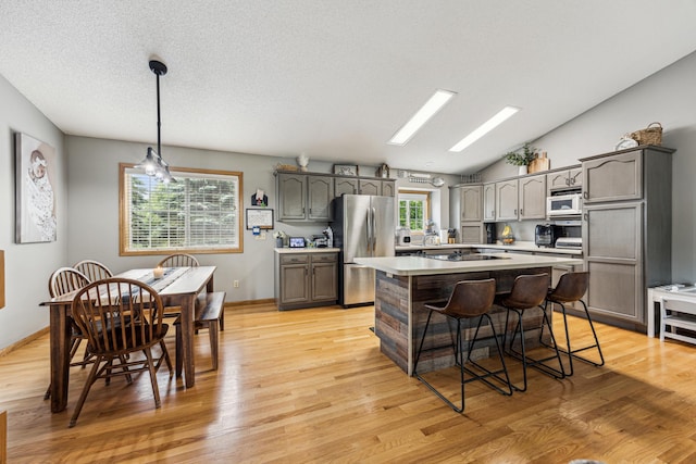 620 Acacia Dr S, Annandale, MN 55302 - kitchen with freestanding refrigerator, white microwave, light wood finished floors, a kitchen island, and vaulted ceiling