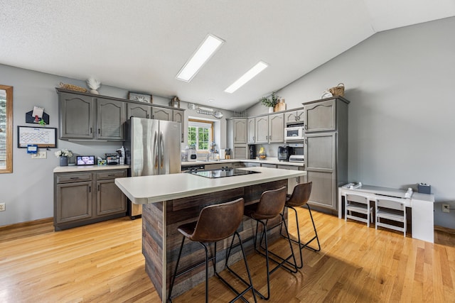 620 Acacia Dr S, Annandale, MN 55302 - kitchen with vaulted ceiling, freestanding refrigerator, black electric stovetop, a breakfast bar, and light wood finished floors