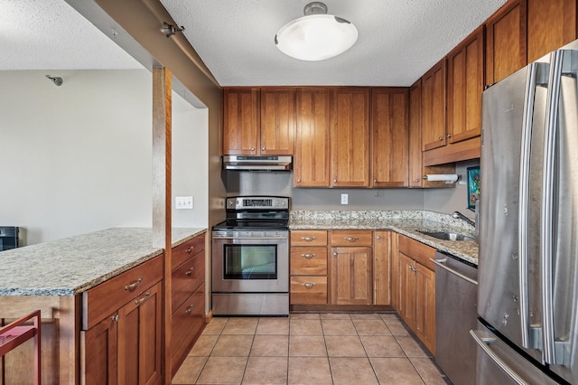 78 10th St E Unit 2901, Saint Paul, MN 55101 - kitchen featuring stainless steel appliances, a textured ceiling, brown cabinets, under cabinet range hood, and light tile patterned floors