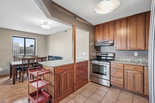 78 10th St E Unit 2901, Saint Paul, MN 55101 - kitchen featuring stainless steel electric stove, under cabinet range hood, a peninsula, brown cabinetry, and light stone countertops