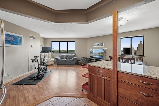 78 10th St E Unit 2901, Saint Paul, MN 55101 - kitchen featuring light wood-style floors, light stone counters, brown cabinetry, a textured ceiling, and open floor plan