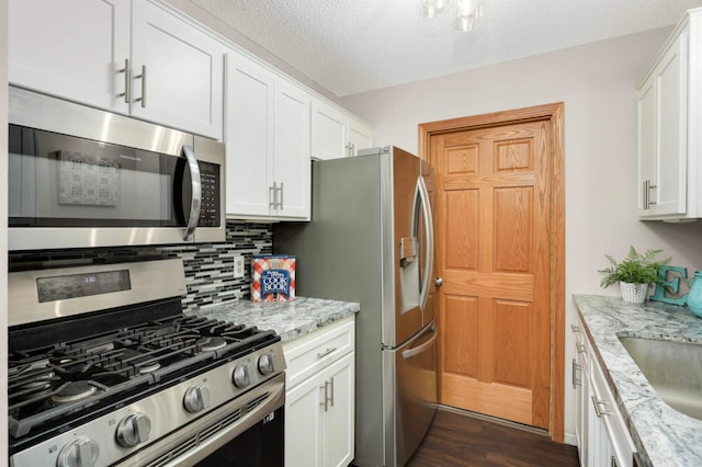 8824 134th St W, Apple Valley, MN 55124 - kitchen featuring stainless steel appliances, decorative backsplash, white cabinets, dark wood-style flooring, and a textured ceiling