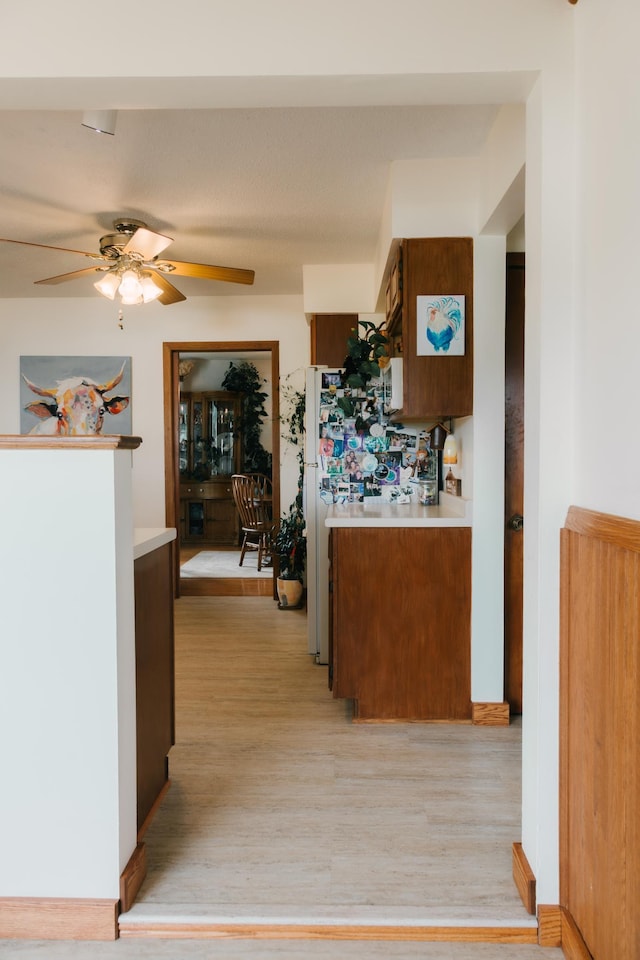 2834 150th St, Luck, WI 54837 - kitchen featuring light countertops, light wood finished floors, ceiling fan, and brown cabinets
