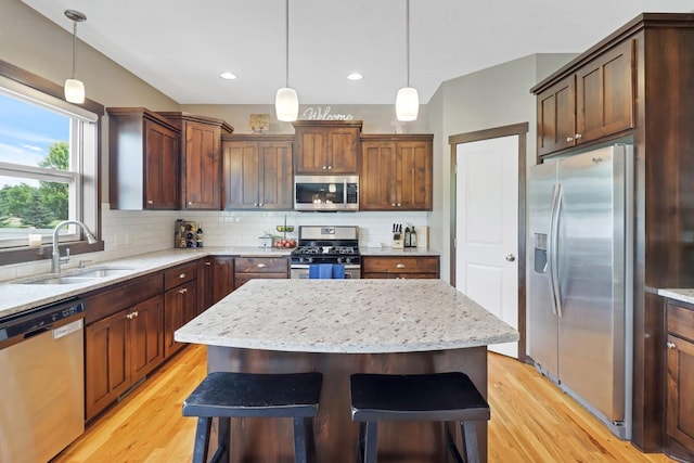 369 144th Ln NW, Andover, MN 55304 - kitchen featuring appliances with stainless steel finishes, light wood-style flooring, decorative backsplash, a center island, and decorative light fixtures