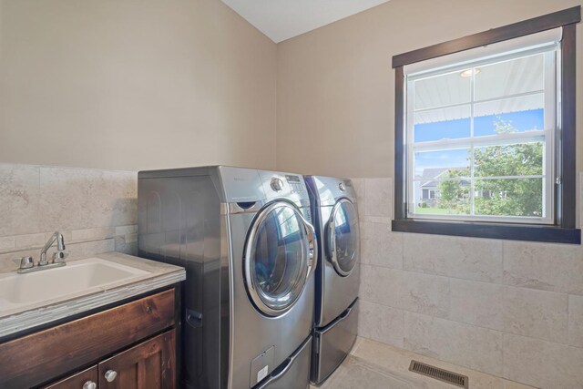 369 144th Ln NW, Andover, MN 55304 - washroom featuring washing machine and dryer, tile walls, cabinet space, and a wainscoted wall