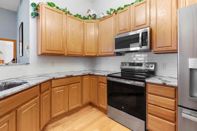 1978 110th Ct NE Unit 1103, Blaine, MN 55449 - kitchen featuring appliances with stainless steel finishes, light wood finished floors, backsplash, and light stone countertops