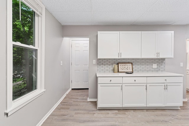 59 Winnipeg Ave, Saint Paul, MN 55117 - kitchen with white cabinetry, light countertops, tasteful backsplash, light wood finished floors, and a paneled ceiling