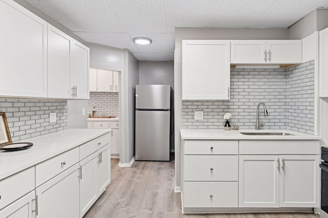 59 Winnipeg Ave, Saint Paul, MN 55117 - kitchen featuring freestanding refrigerator, a paneled ceiling, white cabinets, decorative backsplash, and light wood-type flooring