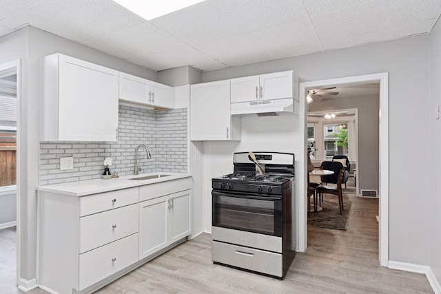 59 Winnipeg Ave, Saint Paul, MN 55117 - kitchen with stainless steel gas stove, under cabinet range hood, light countertops, white cabinets, and decorative backsplash