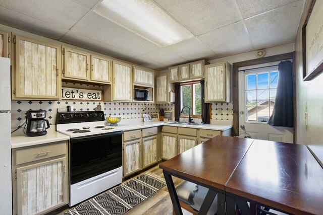 312 5th Ave, Bovey, MN 55709 - kitchen with electric stove, black microwave, light brown cabinets, a paneled ceiling, and light countertops