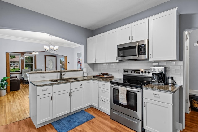 242 Winona St W, West Saint Paul, MN 55118 - kitchen featuring stainless steel appliances, a peninsula, a chandelier, white cabinets, and ornamental molding