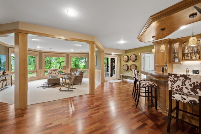 6300 78th Ln, Greenfield, MN 55357 - kitchen with glass insert cabinets, wood finished floors, a kitchen bar, backsplash, and recessed lighting