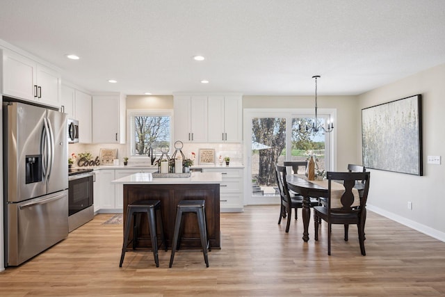 6676 Jason Ave NE, Monticello, MN 55362 - kitchen featuring appliances with stainless steel finishes, a chandelier, white cabinetry, a center island, and plenty of natural light