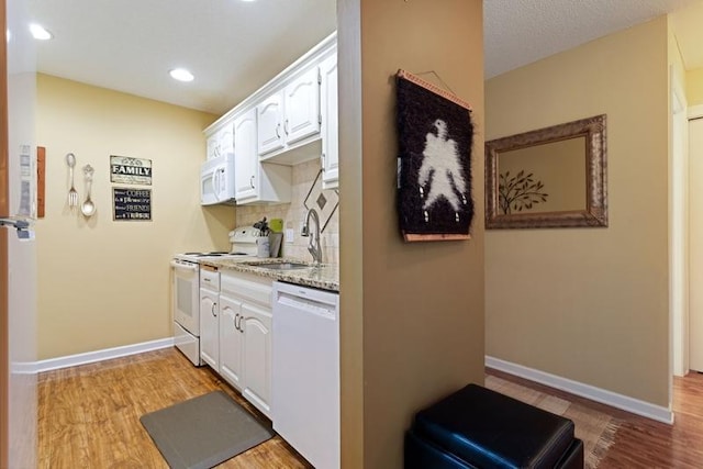 35 Nathan Ln N Unit 104, Plymouth, MN 55441 - kitchen with white appliances, white cabinets, light wood-style floors, backsplash, and light stone counters