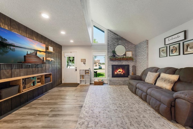 2585 3rd Ave NE, Owatonna, MN 55060 - living room featuring a textured ceiling, wood finished floors, a fireplace, vaulted ceiling, and recessed lighting