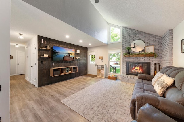 2585 3rd Ave NE, Owatonna, MN 55060 - living area with a brick fireplace, lofted ceiling, a textured ceiling, and wood finished floors