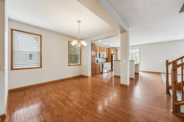 6773 Urbandale Ln N, Maple Grove, MN 55311 - unfurnished living room featuring hardwood / wood-style floors, a chandelier, stairs, and a textured ceiling