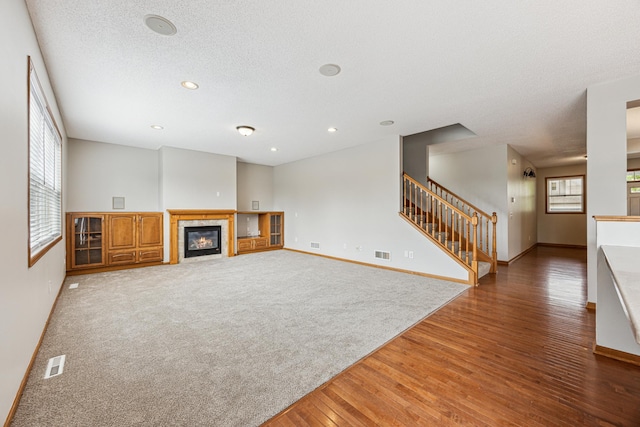 6773 Urbandale Ln N, Maple Grove, MN 55311 - unfurnished living room featuring stairway, light wood-type flooring, a fireplace, recessed lighting, and a textured ceiling