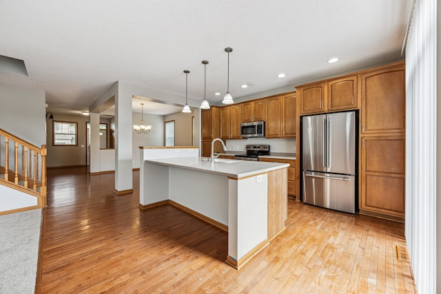 6773 Urbandale Ln N, Maple Grove, MN 55311 - kitchen featuring appliances with stainless steel finishes, light wood-style floors, brown cabinetry, light countertops, and a chandelier
