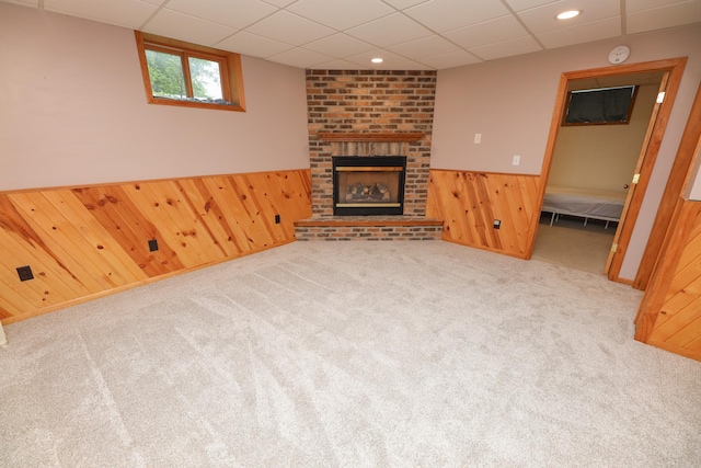 17 Lake St, Osakis, MN 56360 - unfurnished living room featuring wood walls, a brick fireplace, wainscoting, a drop ceiling, and carpet