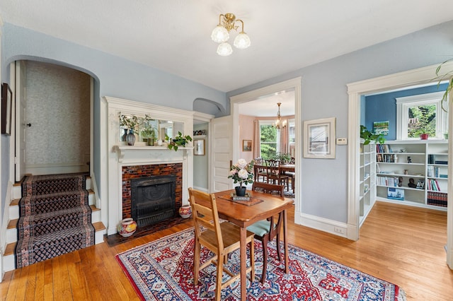 2145 Knapp St, Saint Paul, MN 55108 - dining area with a chandelier, light wood-type flooring, arched walkways, and a fireplace