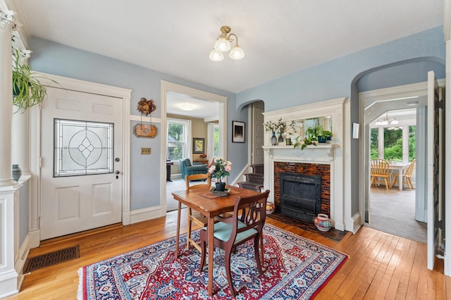 2145 Knapp St, Saint Paul, MN 55108 - dining area with a chandelier, light wood-type flooring, a fireplace, and arched walkways