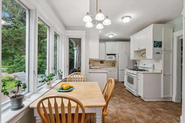 2145 Knapp St, Saint Paul, MN 55108 - kitchen with white appliances, light countertops, white cabinetry, backsplash, and a chandelier
