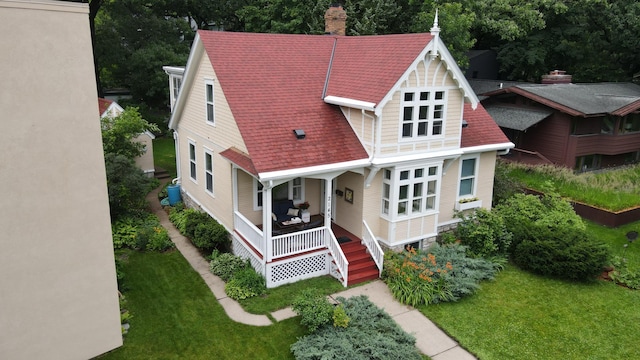 2145 Knapp St, Saint Paul, MN 55108 - view of front of house with covered porch, a chimney, a front lawn, and a shingled roof