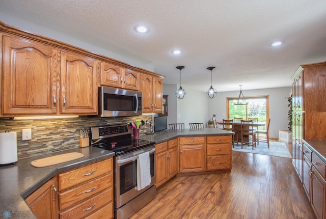633 Leonards Way, Argusville, ND 58005 - kitchen featuring appliances with stainless steel finishes, dark countertops, dark wood-style floors, brown cabinetry, and recessed lighting