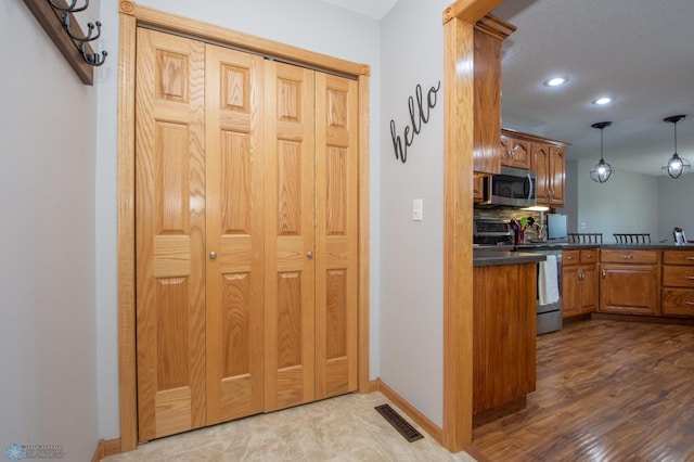 633 Leonards Way, Argusville, ND 58005 - kitchen with stainless steel appliances, dark countertops, brown cabinetry, recessed lighting, and decorative backsplash