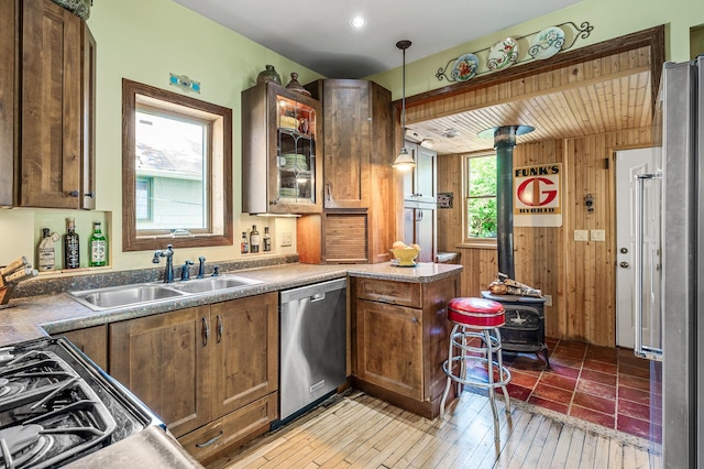 3231 41st Ave S, Minneapolis, MN 55406 - kitchen featuring dishwasher, a wood stove, wood walls, a peninsula, and pendant lighting