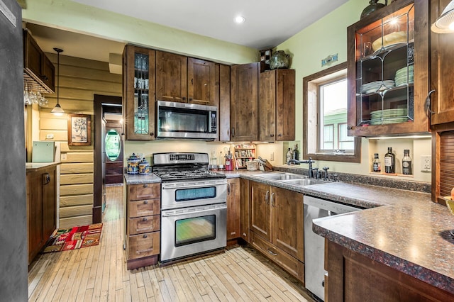 3231 41st Ave S, Minneapolis, MN 55406 - kitchen with appliances with stainless steel finishes, dark countertops, light wood-style flooring, glass insert cabinets, and decorative light fixtures