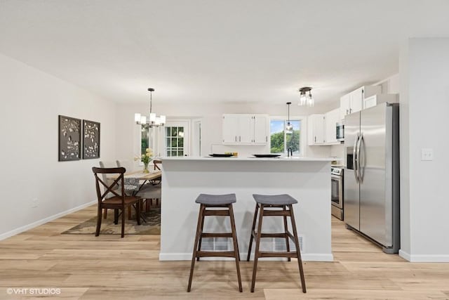 9019 Idaho Ave N, Brooklyn Park, MN 55445 - kitchen with appliances with stainless steel finishes, light wood finished floors, white cabinetry, a chandelier, and light countertops