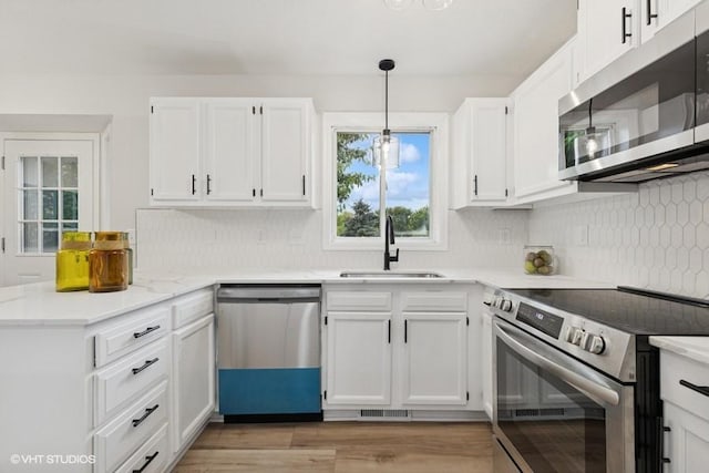 9019 Idaho Ave N, Brooklyn Park, MN 55445 - kitchen featuring appliances with stainless steel finishes, a peninsula, and white cabinetry