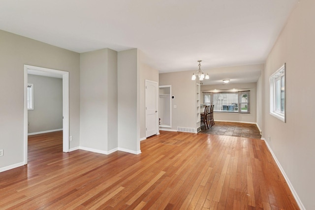 724 Pierce St NE, Minneapolis, MN 55413 - unfurnished living room with light wood-style flooring and a chandelier