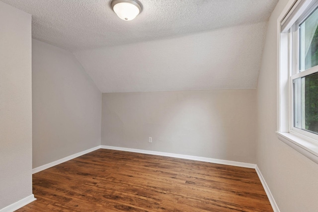 724 Pierce St NE, Minneapolis, MN 55413 - additional living space with vaulted ceiling, wood finished floors, and a textured ceiling