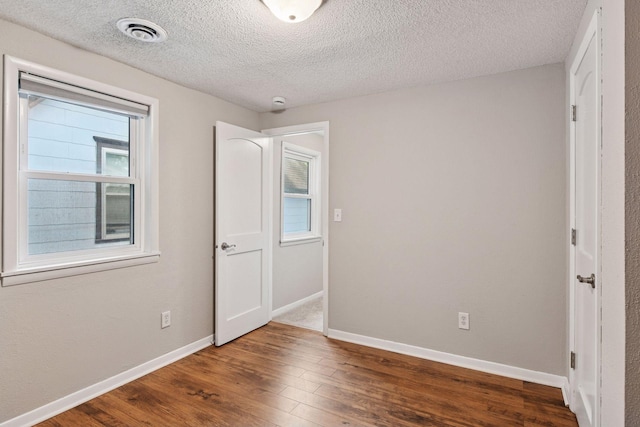 724 Pierce St NE, Minneapolis, MN 55413 - unfurnished bedroom with wood finished floors and a textured ceiling