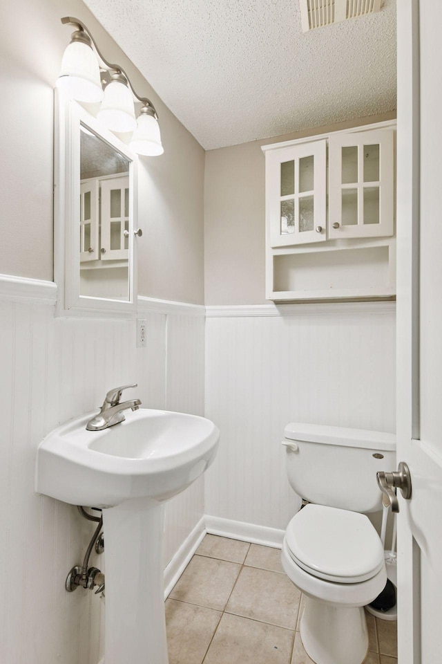 724 Pierce St NE, Minneapolis, MN 55413 - bathroom featuring wainscoting, a textured ceiling, and tile patterned flooring