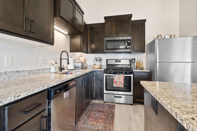 8468 Gateway Cir, Monticello, MN 55362 - kitchen with appliances with stainless steel finishes, dark brown cabinets, backsplash, light wood-style floors, and light stone countertops