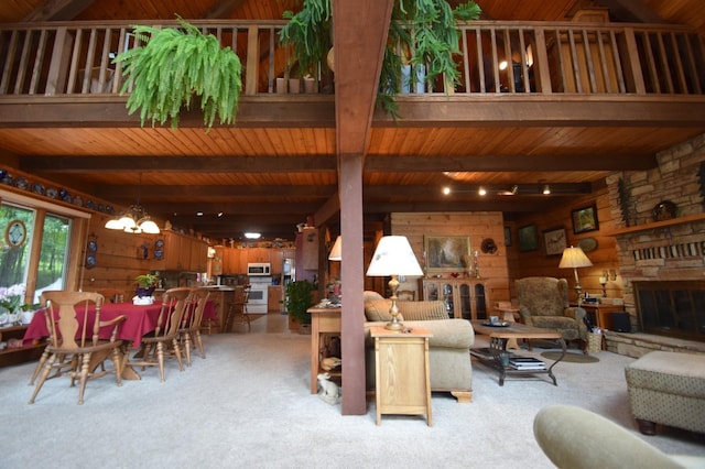 28716 Kilkare Rd, Danbury, WI 54830 - living room featuring light carpet, wood walls, a wood ceiling with exposed beams, a stone fireplace, and a chandelier