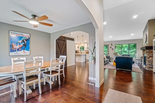 1115 Timber Path, Menomonie, WI 54751 - dining area featuring hardwood / wood-style flooring, arched walkways, ceiling fan, a fireplace, and a barn door