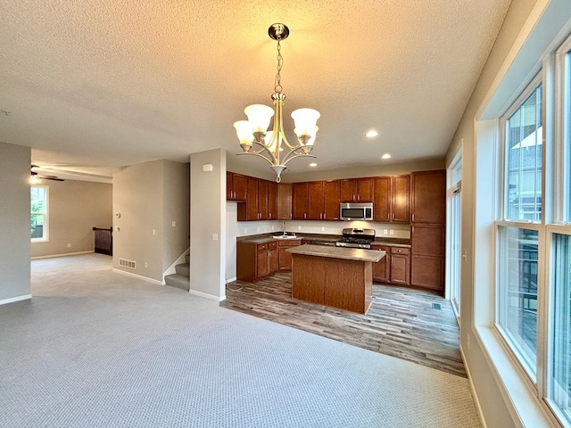 8389 Norwood Ln N, Maple Grove, MN 55369 - kitchen with appliances with stainless steel finishes, open floor plan, a textured ceiling, a chandelier, and a center island