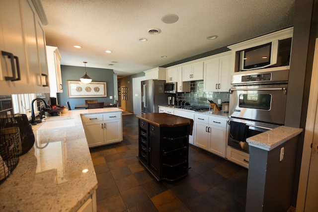 701 Oak Ave, Olivia, MN 56277 - kitchen with appliances with stainless steel finishes, a peninsula, decorative backsplash, white cabinets, and light stone counters