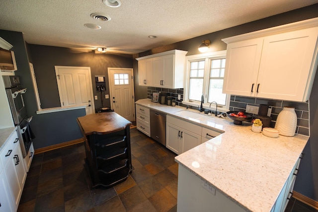 701 Oak Ave, Olivia, MN 56277 - kitchen with stainless steel appliances, backsplash, white cabinetry, a textured ceiling, and a peninsula