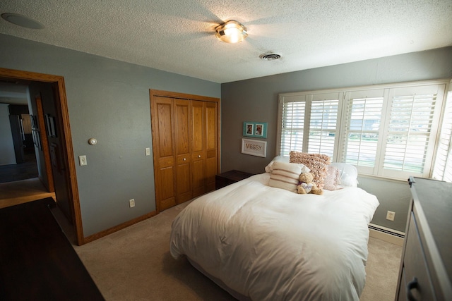 701 Oak Ave, Olivia, MN 56277 - bedroom featuring a textured ceiling, light colored carpet, a closet, a baseboard radiator, and ceiling fan